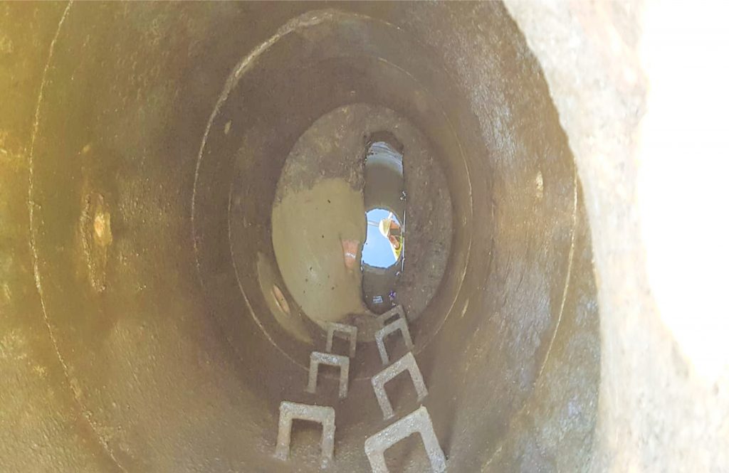 a manhole showing the rungs of steps leading down into the sewer.